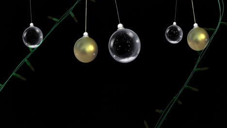 luces amarillas de cuerda de navidad parpadeando sobre oro balanceado y bolas claras sobre fondo negro