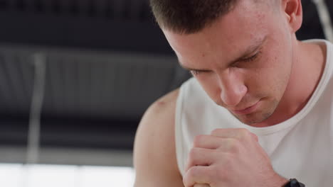 close up of man with focused expression performing squat variation in modern gym studio with soft natural light and industrial ceiling design highlighting intensity and concentration during workout
