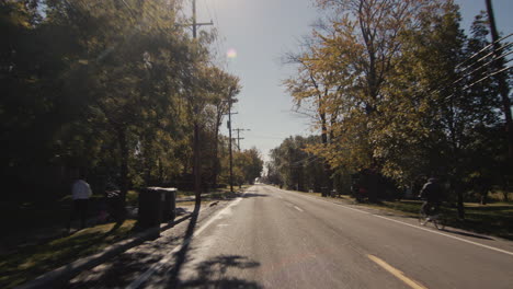 Driving-on-a-scenic-country-road-on-an-autumn-day,-the-view-from-the-back-window-of-a-car.