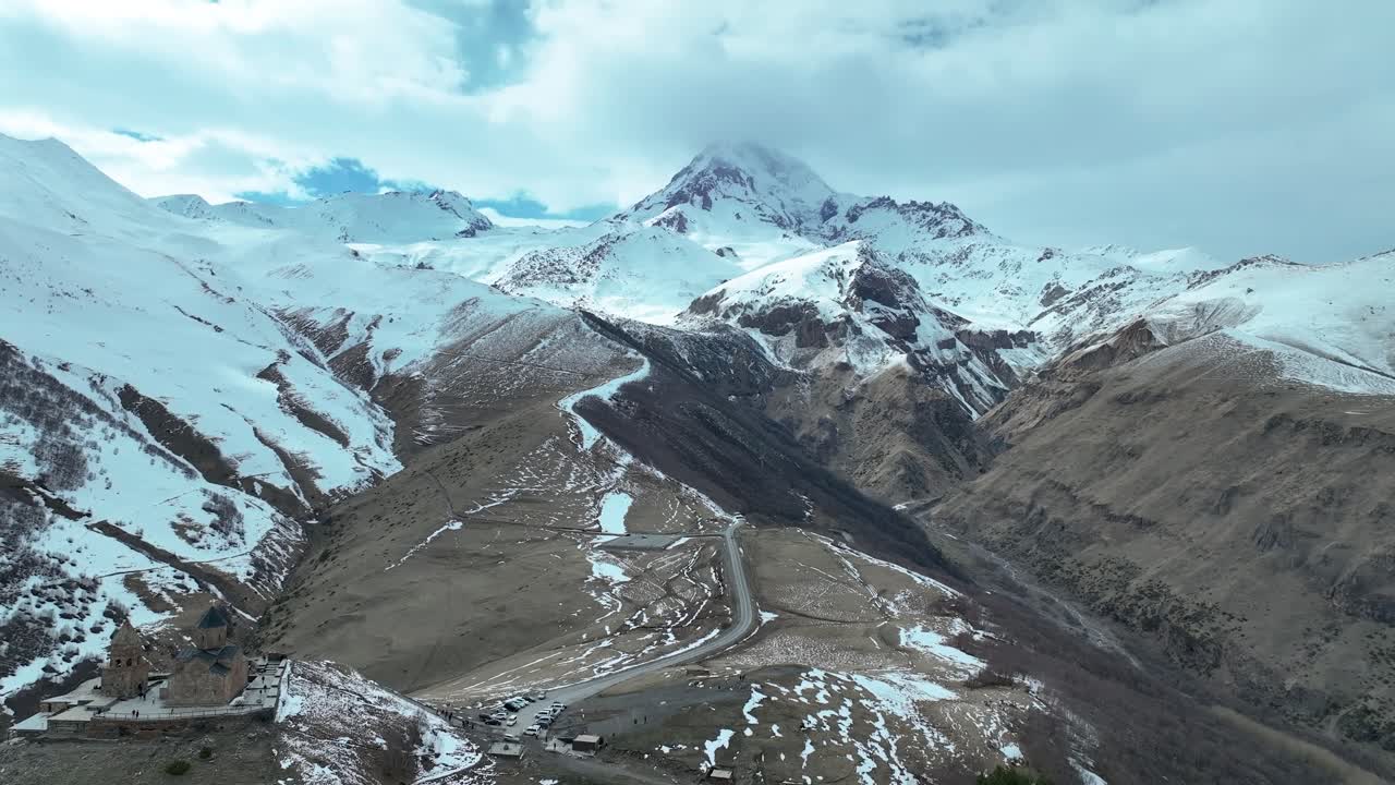 volando junto a la iglesia de la trinidad de gergeti hacia el monte kazbek en georgia - disparo de avión no tripulado
