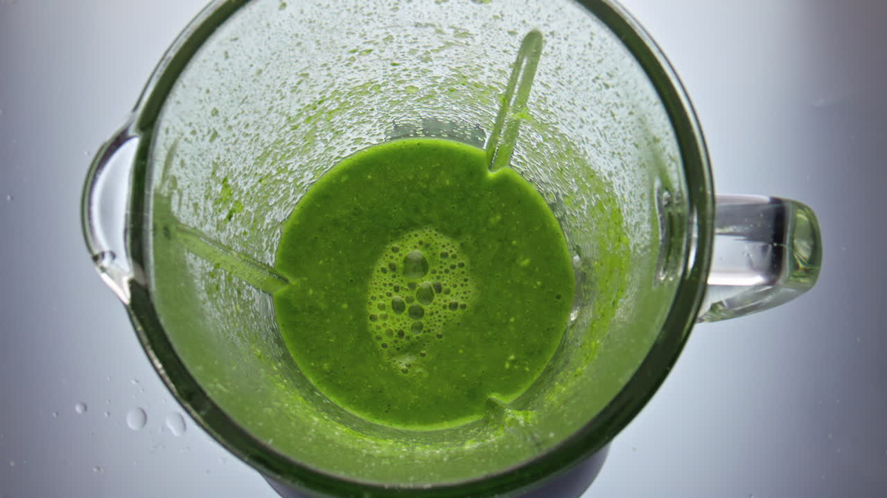 un batido verde de primer plano preparándose en una licuadora a cámara súper lenta. un cóctel saludable.