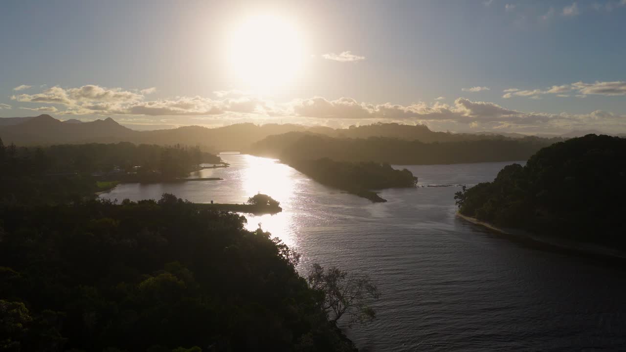 Aerial view of a serene river landscape at sunset, highlighting the tranquil water and lush surroundings with warm lighting