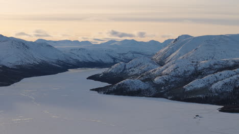 a dramatic aerial shot of whitehorse, yukon, highlighting the rugged terrain, golden horn, mount sumanik, and vast snow-covered landscapes during sunset in the heart of winter.