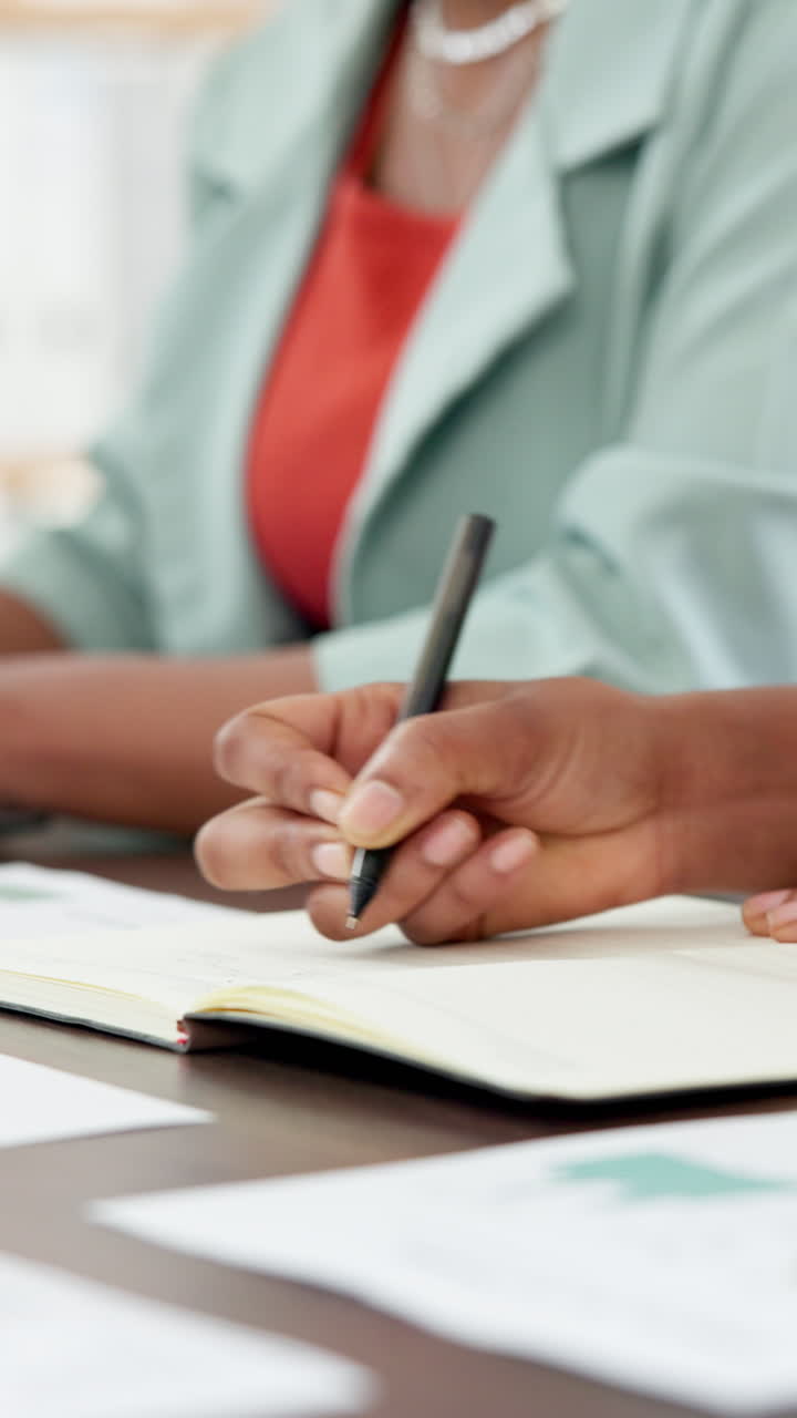 Primo piano di mani che scrivono su un quaderno durante una riunione di lavoro