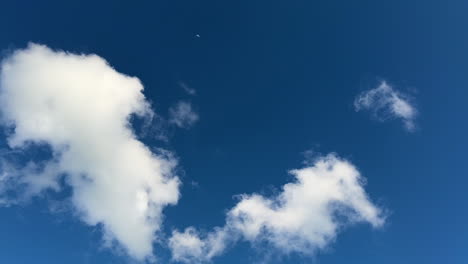 blue sky with fast-moving white clouds drifting across the frame. the scene captures atmospheric movement on a bright day.