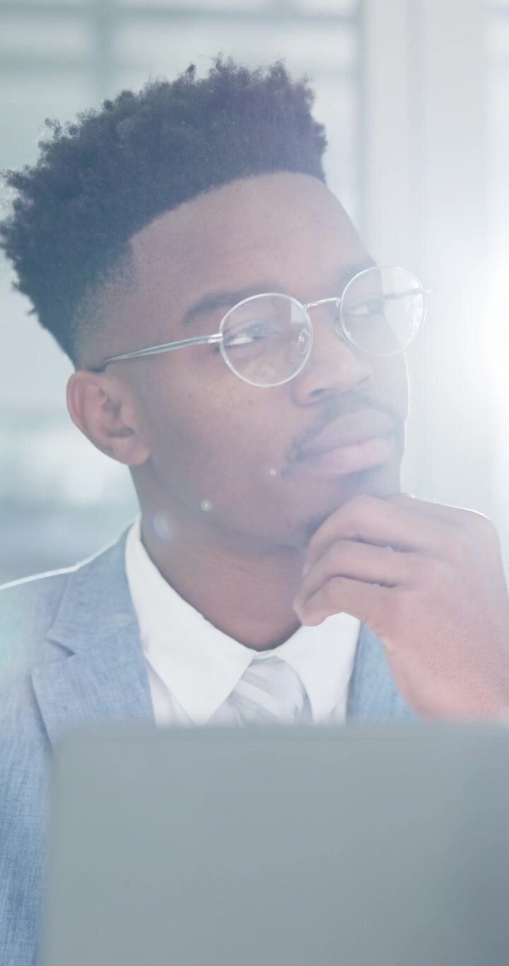 Young Professional Man Thinking While Working on Laptop in Office