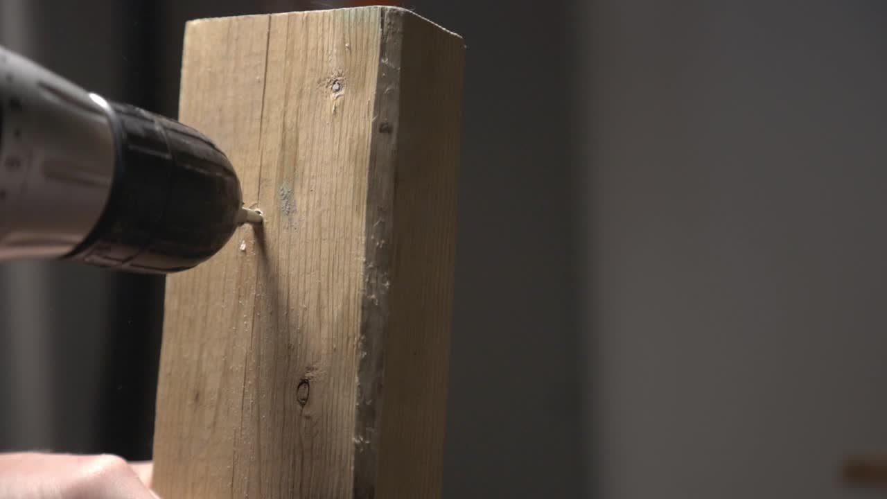 A Carpenter Using An Electric Drill To Make A Hole Into The Piece Of Wood. Woodworking. - close up shot