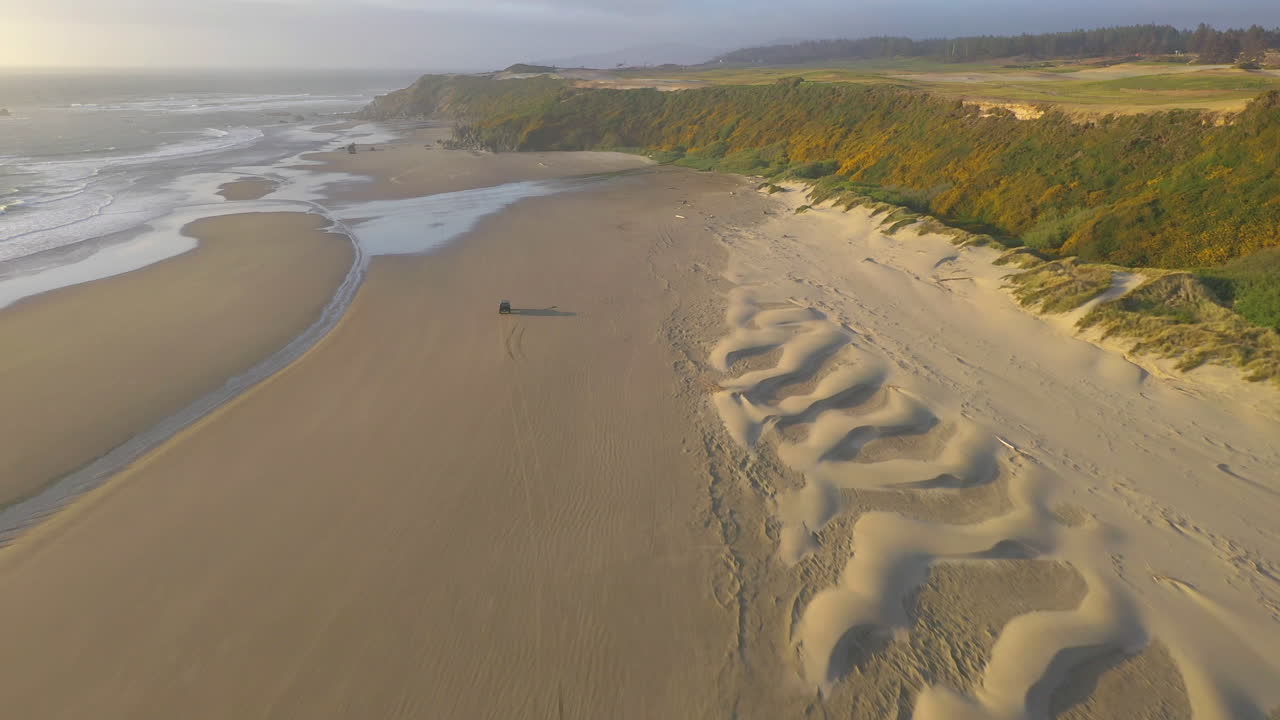 drone siguiendo a un auto a toda velocidad en una playa de oregon