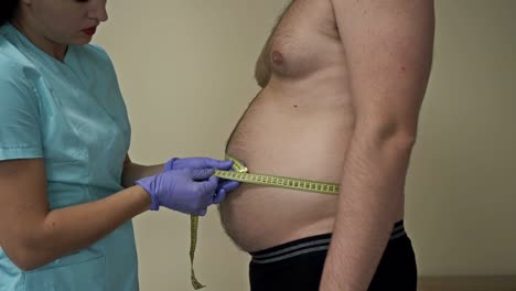 doctor measures the abdominal circumference of an overweight patient