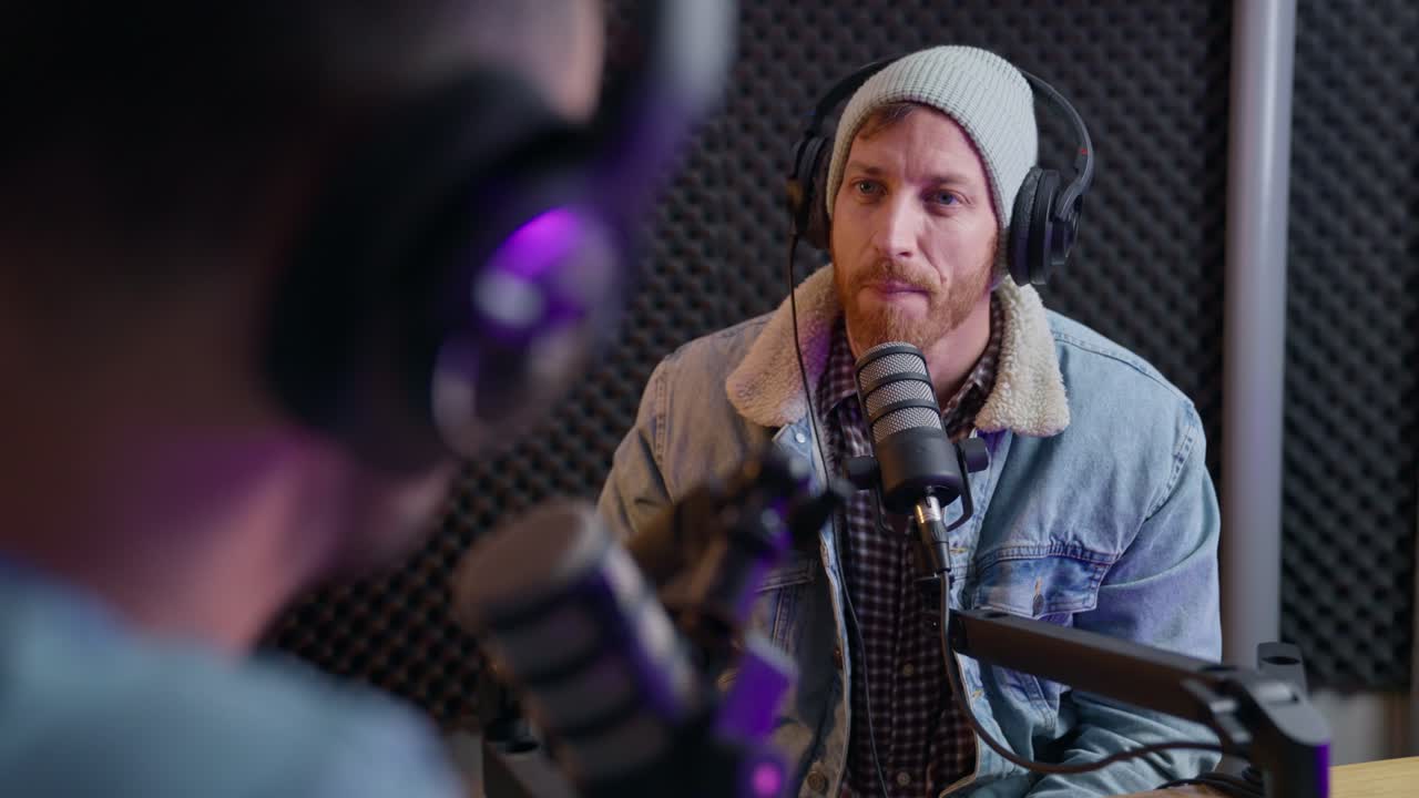 dos hombres hablan en un programa de radio o podcast. anfitrión entrevistando a un invitado en transmisión en vivo en un estudio de sonido. hablando e interactuando entre sí con micrófonos y auriculares y equipo de audio profesional