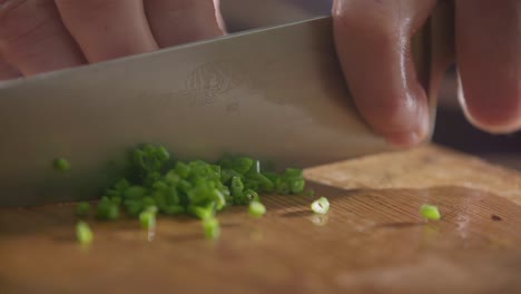 chopping fresh green onions on wooden cutting board