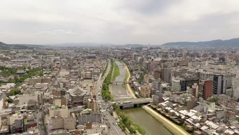 Colorful-wide-aerial-of-Kyoto-with-Kamo-river,-temples,-mountains,-and-city-skyline-in-Kyoto,-Japan