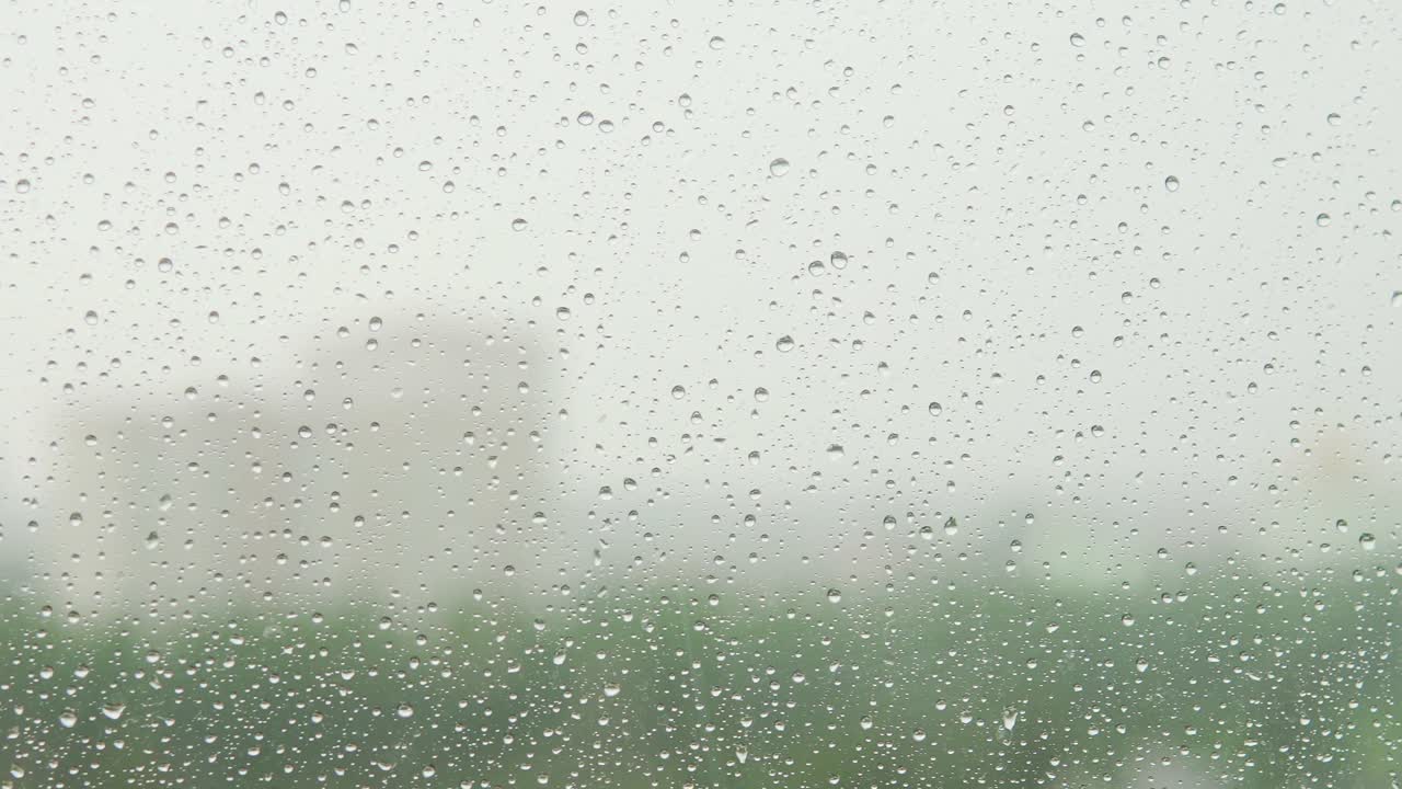 gotas de lluvia en la ventana. edificios y árboles en un fondo borroso.
