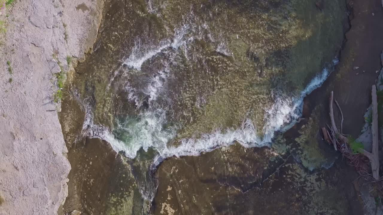 un río con rápidos poco profundos y agua clara que fluye sobre las rocas durante una carrera de salmón, vista aérea