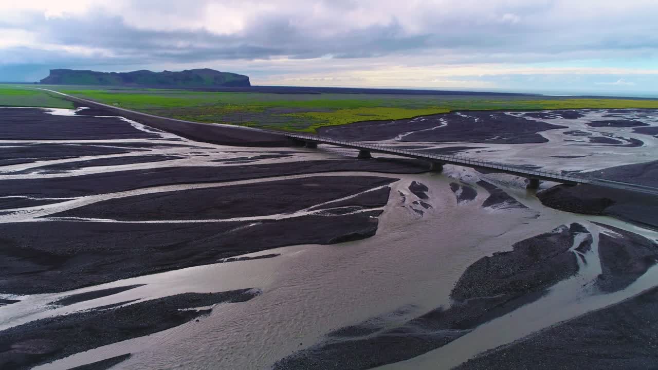 아이슬란드의 크고 어두운 화산 홍수 강 시스템을 가로지르는 도로와 다리를 따라 자동차의 공중