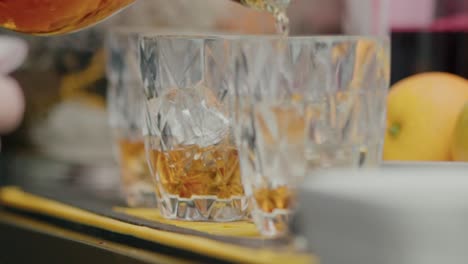 close up of whiskey being poured into crystal glasses