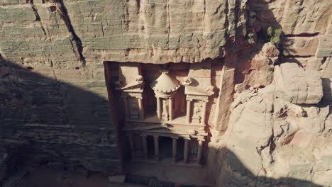 seguimiento aéreo de la fachada cortada en roca del tesoro en una pared de roca de piedra arenisca, petra, vista de drone de alto ángulo