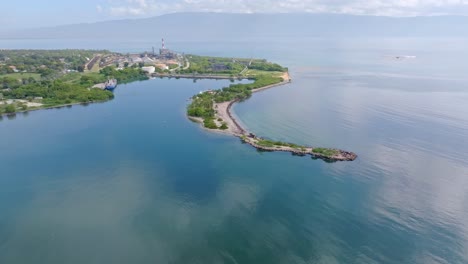 Descending-drone-shot-of-Neiba-Bay-with-island-and-beach-el-cayo-during-sunny-day,-Domincan-Republic