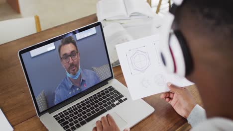 African-american-male-college-student-holding-notes-while-having-a-video-call-on-laptop-at-home