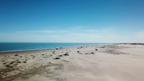 vista de ángulo bajo de drones aéreos de dunas de arena en la isla barrera de la costa del golfo en una tarde soleada, moviéndose hacia la playa en el golfo de méxico - isla del padre sur, texas