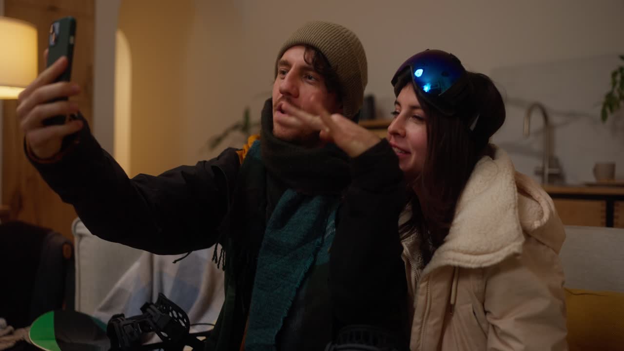 Couple taking a selfie at home after a snowboarding trip
