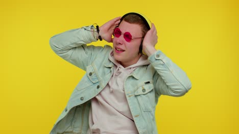 cheerful attractive man listening music via headphones and dancing disco fooling around having fun