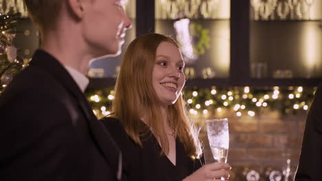 close up view of group friends wearing stylish clothes while talking and holding champagne glasses at new year's party 1