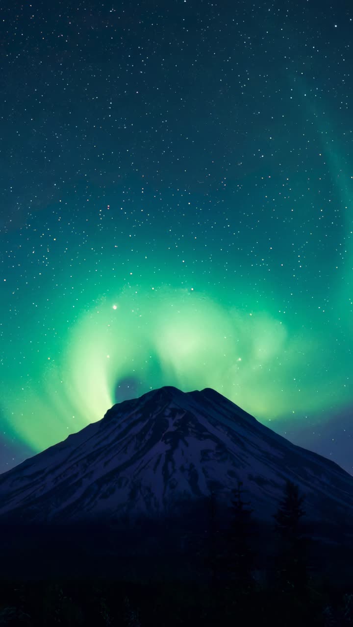 Vertical video: Shifting aurora driven by sun, forming beam above snow peak at night, with stars