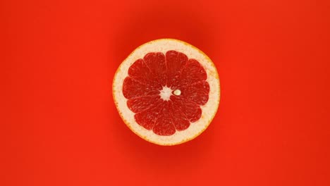 grapefruit fruit isolated on red background, rotate.