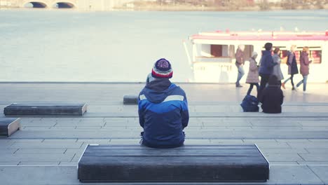 person sitting on bench by the river