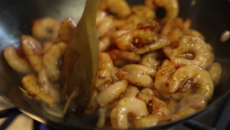 Wooden-Spoon-Stirring-Frozen-Prawns-Inside-Heated-Wok