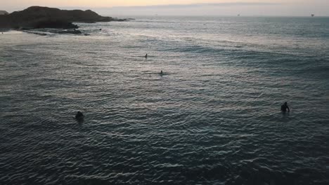 Calming-aerial-drone-view-of-the-ocean-with-a-surfboard-and-surfers-waiting-in-South-america