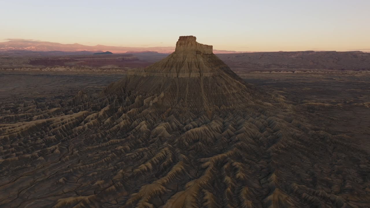 Wide aerial landscape with Factory Butte and surrounding Utah desert terrain, panoramic overview of orange glow on winding tendrils