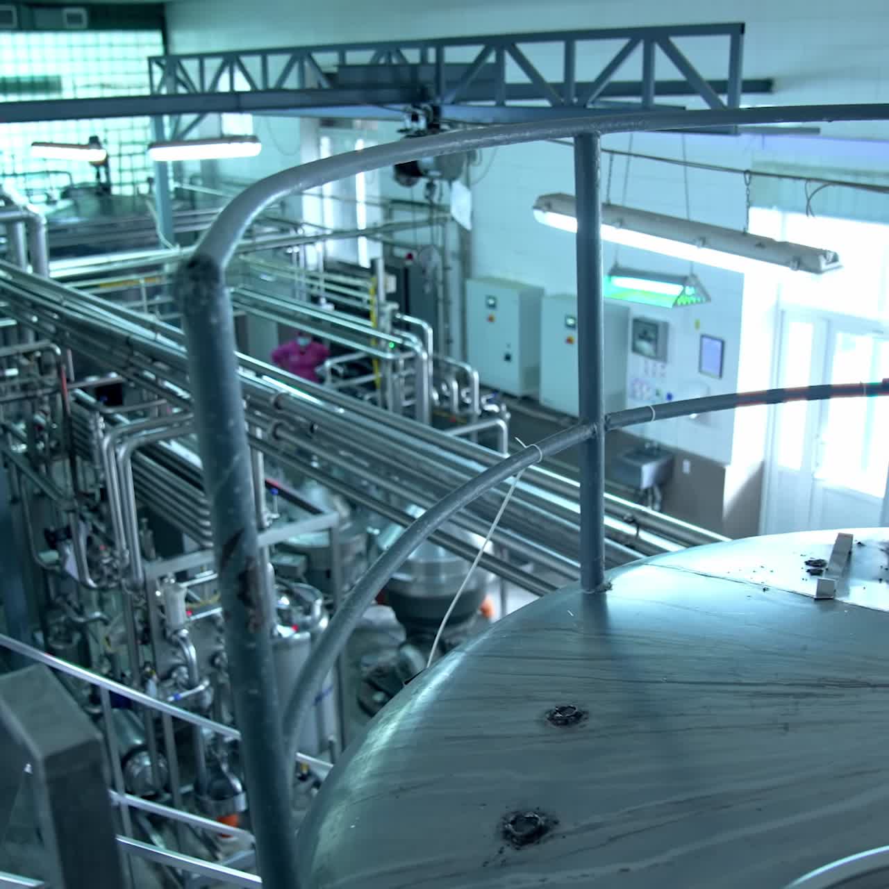 Tops of enormous steel tanks. Metal reservoirs risen above the other technological devices. Large windows at the backdrop