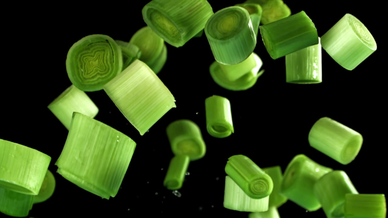 Fresh Sliced Leeks Falling in Slow Motion on Black Background