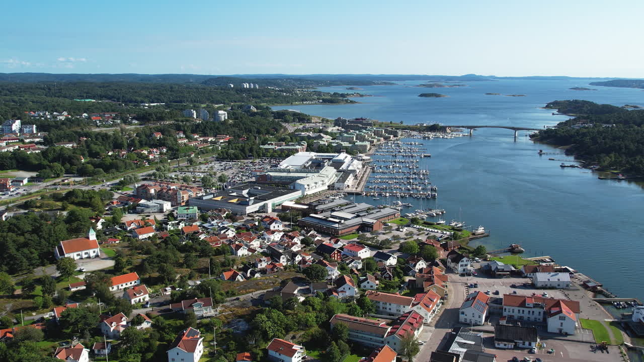 Parallax drone shot of Stenungsund harbor with boats, bridge and blue water in the day in Bohuslan, Sweden
