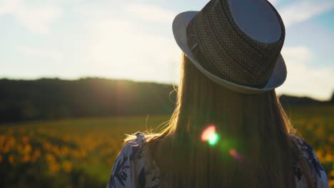 stunning hd footage of a white caucasian girl in a dress with a knitted hat and red lipstick stands in a field, embracing the fading sunlight