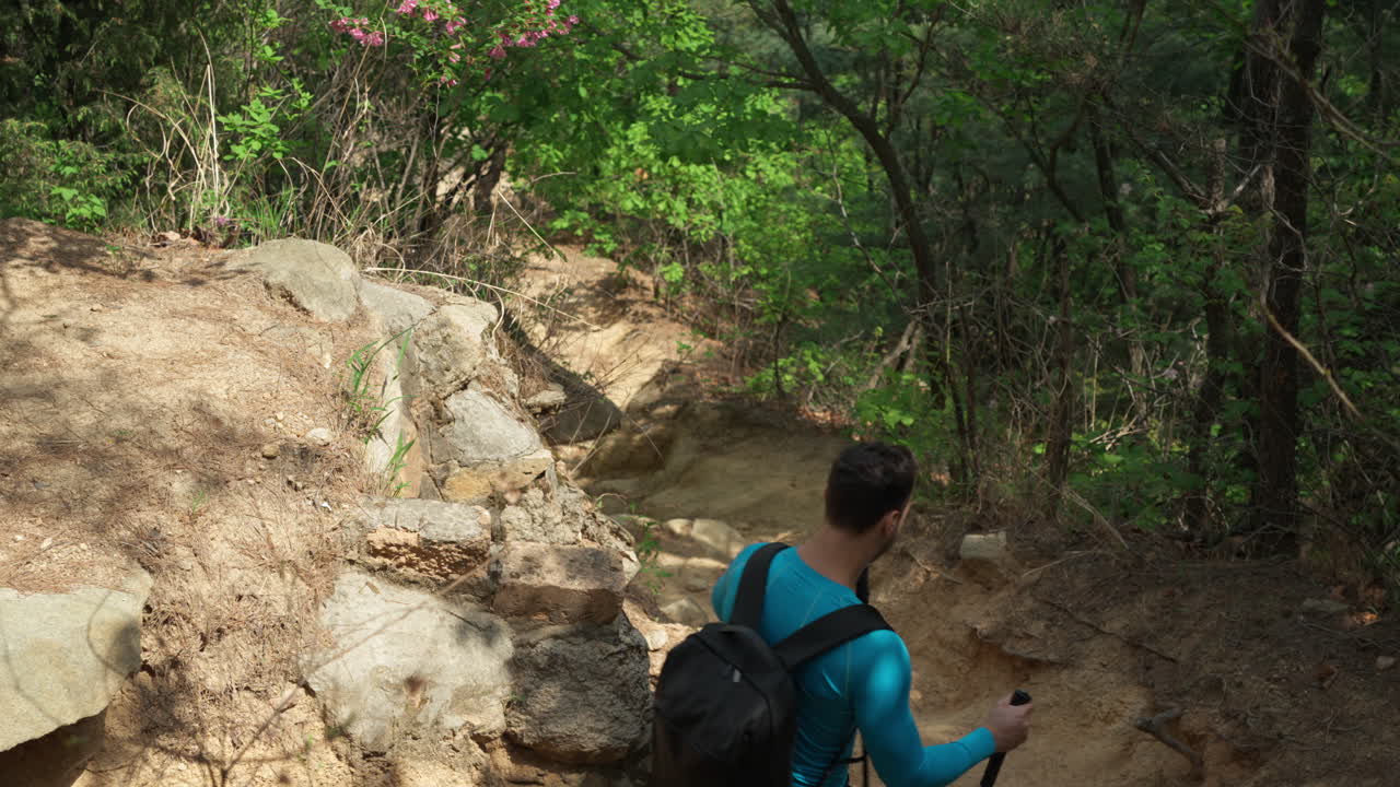 hombre en forma con una mochila camina por el sendero rocoso en un hermoso paisaje de bosque de primavera