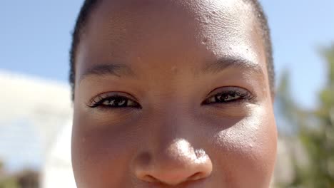 retrato de una feliz mujer afroamericana mirando a la cámara en la casa de la playa
