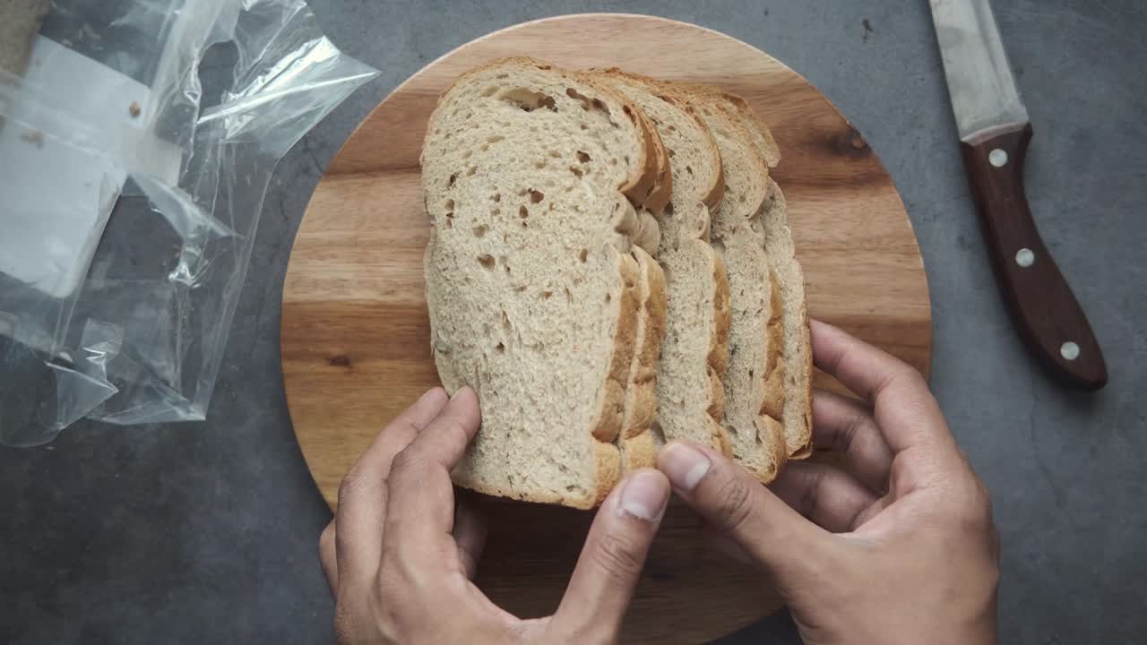 putting slice of brown baked bread on chopping board