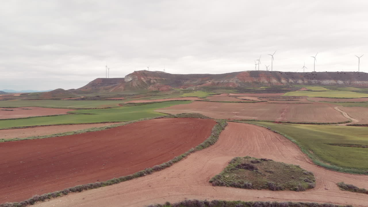 tierras de cultivo rojas y verdes con algunos molinos de viento en el horizonte