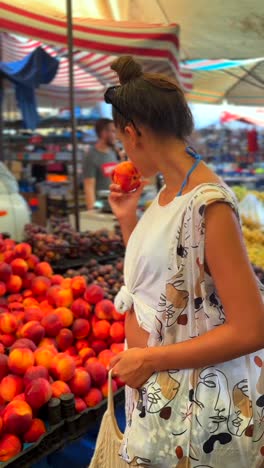 woman shopping for peaches at a market