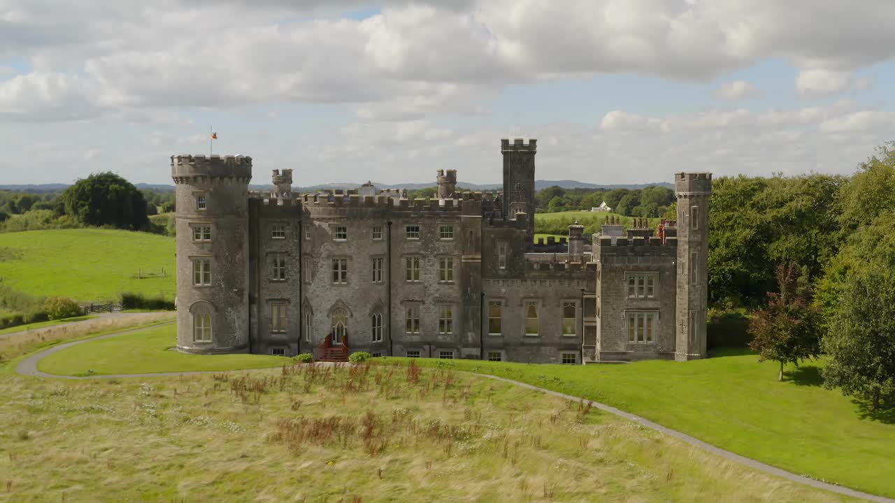 Wide aerial dolly shot of the back of a beautiful Irish castle, revealing its architecture and surroundings