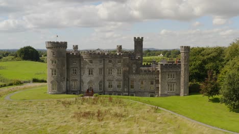 wide aerial dolly shot of the back of a beautiful irish castle, revealing its architecture and surroundings