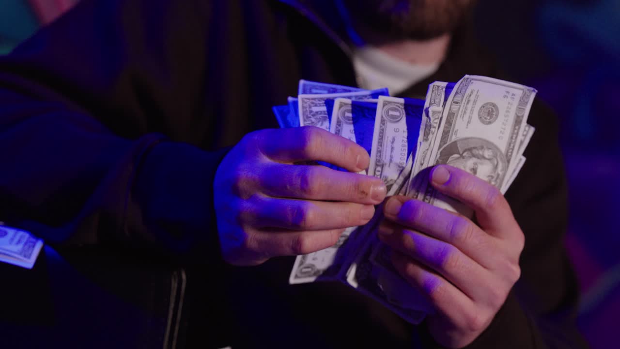 Dark, cinematic stock footage showing a person counting cash under dramatic lighting, symbolizing illegal income, criminal activity, corruption, and money earned through unlawful means