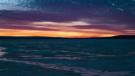 dramatic sunset timelapse at an icy lake, sunlight colors reflecting on clouds