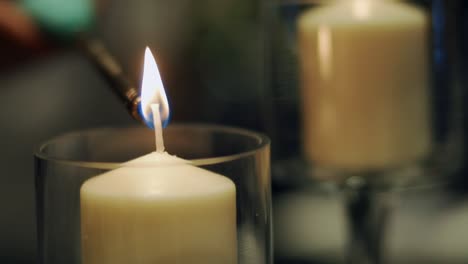 white candles inside a glass candle holder being lit