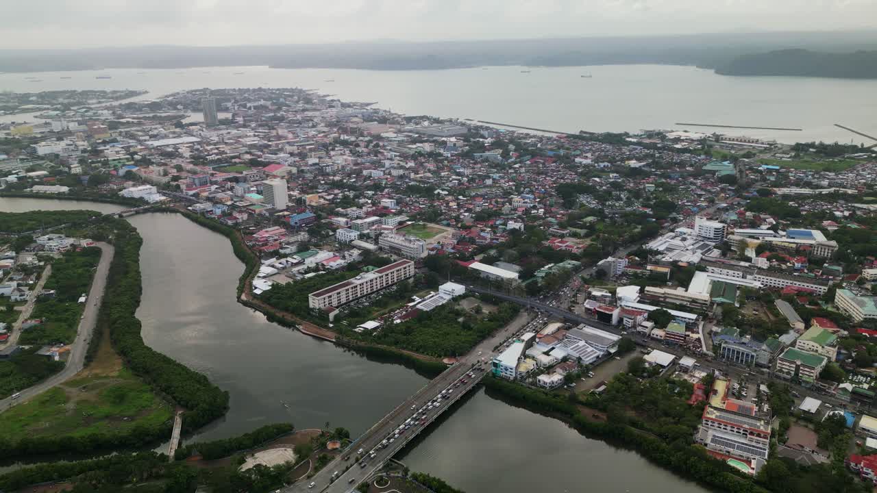 Ripresa aerea con drone della città di Iloilo che mostra un denso sviluppo urbano, un fiume, un ponte e un paesaggio costiero sul lungomare nelle Visayas, Filippine