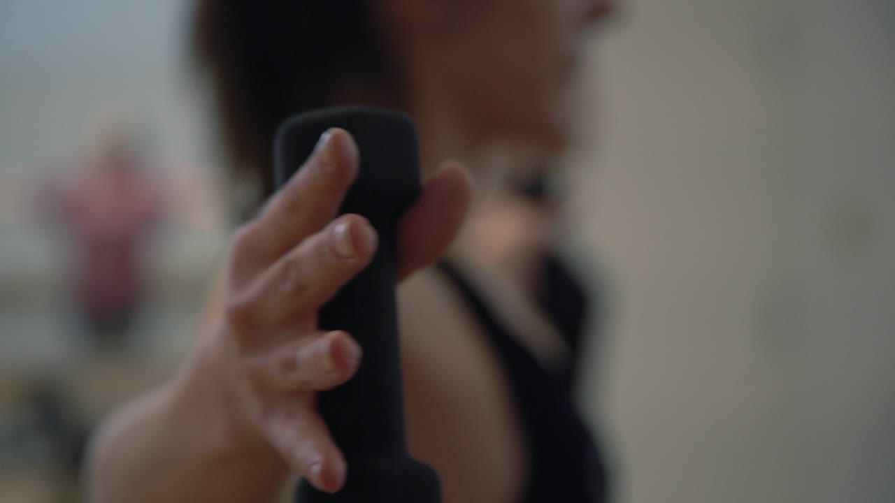 un primer plano de las manos de una dama en un gimnasio ejerciendo sus manos con pequeñas pesas en un gimnasio