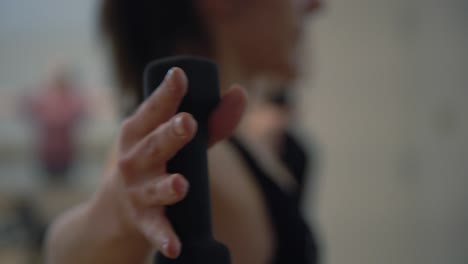 un primer plano de las manos de una dama en un gimnasio ejerciendo sus manos con pequeñas pesas en un gimnasio